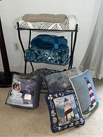 Weighted blanket, decorative throw pillows with nautical designs, folded blankets on black metal blanket rack.