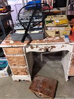 Fishing net laid on top of an open tackle box showing compartments and various fishing lures, on a worn wooden desk.
