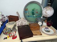 Full lot view on table showing all items clearly, including sailing tray, globe, tin clock, paperweight, keepsake boxes and glass pieces.