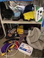 Shelf with marine and outdoor equipment including oil pump, first aid kit, cables, ski lines, and boxes
