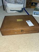 Wooden flatware chest closed on carpet with brass plate on lid