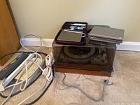 United Audio Dual 1019 turntable with dust cover, multiple surge protector power strips and extension cord visible on floor.