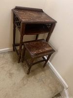 Vintage wooden telephone table with lattice side design and veneer wear, water stains visible on surface. Matching bench in front.