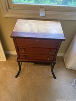 Front view of two drawer wood chest with sailboat design on top and metal frame base
