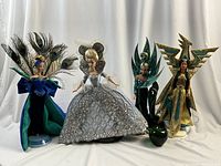 Four dolls displayed in a row showing full outfits and stands