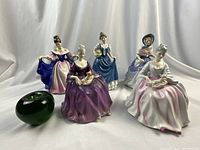 All five figurines displayed with a green apple for scale