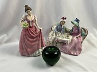 Both figurines displayed with green glass apple for scale