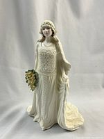 Front view of Coalport porcelain figure in bridal gown holding flower bouquet.