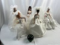 Overview of five Barbie dolls with green apple for scale