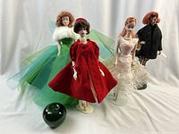 Overview of four dolls displayed with green apple scale reference