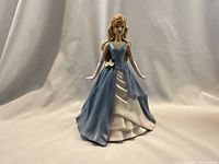 Front view of the Barbie figurine wearing a blue and pink gown with floral detail at waist, standing against a white background.