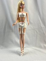 Full front view of doll on stand showing outfit and accessories