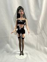 Front view of Barbie in black lingerie, stockings, heels, on display stand