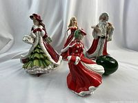 Group of four Royal Doulton Christmas figurines with green apple size reference on white background