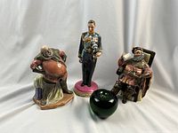 Three Royal Doulton figurines with a green glass apple for size reference