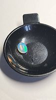 Top-down view of the oval cabochon opal showing multicolor flash inside a black container.