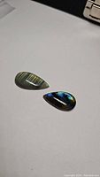 Two pear-shaped labradorite cabochons displaying blue and golden flash on a flat surface.
