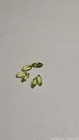 Six marquis cut natural peridot gemstones in apple green color placed on white background.