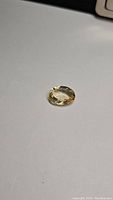 Oval cut golden citrine gemstone shown on neutral surface, highlighting color and clarity.