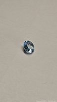 Top view of a round, faceted sky blue topaz gemstone showing light blue color and diamond cut facets.