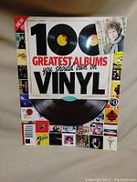 Front cover of the book '100 Greatest Albums You Should Own on Vinyl' showing large bold text and vinyl image with multiple small album cover images around the border.