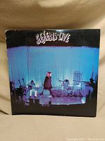 Front cover of Genesis Live vinyl album showing band on stage with lighting and Genesis Live title