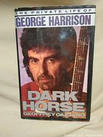 Front cover of the book showing George Harrison holding a guitar, titled 'The Private Life of George Harrison: Dark Horse' by Geoffrey Giuliano.
