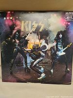 Front cover of Kiss Alive! vinyl LP album featuring band members in stage makeup and costumes with stage smoke effects.