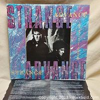 Front cover of Strange Advance album with photo of two band members and colorful abstract pattern