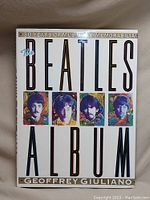 Front cover of The Beatles Album coffee table book showing colorful portraits of the Beatles and title text.