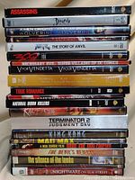 Stack of DVD cases showing titles and spines including action, horror and cult classic movies.
