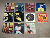 Full collection of 11 Elvis Presley vinyl record albums laid out on floor, showing album covers with assorted colors and Elvis images, including 'Blue Hawaii' and 'Clambake'.