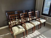Front view of all eight chairs arranged in two rows against a dark wall, showing full set.