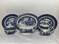 Full set showing two plates, gravy boat, small pitcher, and covered sugar bowl on white cloth background.