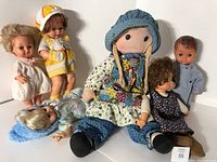Group photo showing vintage Holly Hobbie rag doll seated surrounded by five vintage baby dolls of various styles and clothing.