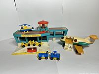 Overview photo showing the Fisher Price Little People airport set including terminal, airplane, helicopter, and small vehicles.