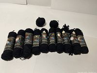 10 skeins of black Nomotta Druida wool yarn laid out in a row showing shape and quantity