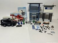Full lot view from front showing all police station structures, vehicles, figures and accessories arranged on table surface.