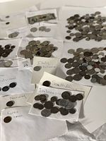Coins sorted and grouped by country labels on paper, showing coins from Italy, Korea, Vietnam, Norway, France, Germany, Mexico, South Africa, Indonesia, and some unidentified.
