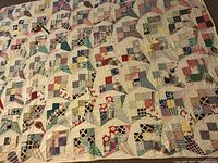 Close-up of antique patchwork quilt showing diverse colored and patterned squares and some fabric wear.