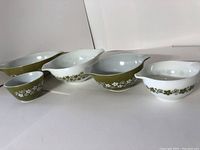 Five vintage Pyrex green and white mix bowls arranged in size order showing floral designs