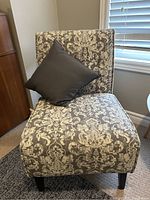 Front view of one fabric accent chair with detailed white and grey damask pattern and a black pillow on the seat.