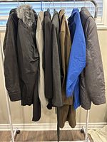 Photo showing 8 women's jackets hanging on a rack with various colors and styles, including one with fur collar.