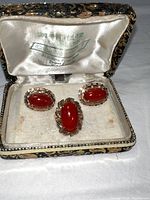 Ring and cuff links set displayed in a vintage fabric-lined box, showing the red acrylic stones and gold settings.