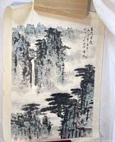 Full view of Asian style mountain pass painting depicting landscape with trees, cliffs, waterfall, pavilion, calligraphy and red seals.