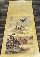Full view of the Asian scroll showing the mountain and valley landscape painting with silk borders and wooden roller.
