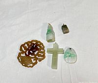 Lot of 5 jadeite pendants displayed on a white cloth, showing size and color variations