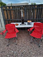 Two red Ozark Trail camping chairs, LP heater, Wilson gloves, and propane stove box on table outdoors