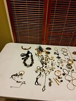 Full view of 40+ craft jewelry items including bracelets, necklaces, earrings, rings, and bangles spread on a white cloth surface.