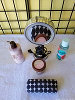 Overview photo showing all items in the lot on a white surface including the makeup mirror, two cosmetic jars, Pink body mist, and cosmetic bag.